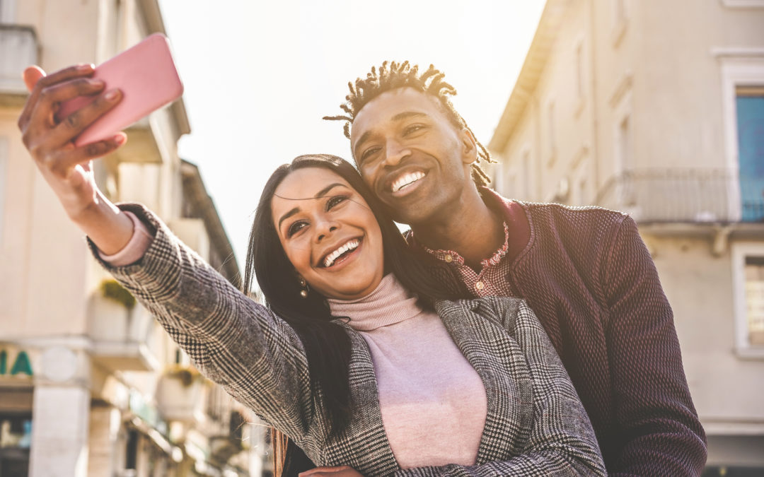 Latin couple taking selfie photo for social network story - Influencers people having fun with new trend technology - Love, fashion and relationship concept - Focus on faces